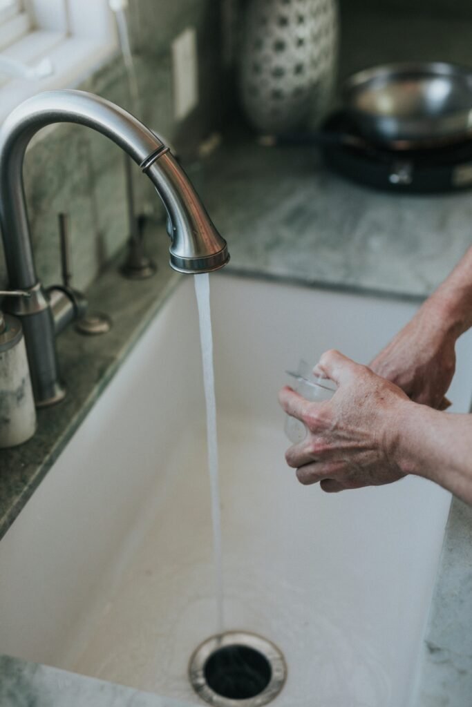 Persona lavando un vaso con agua del grifo abierta