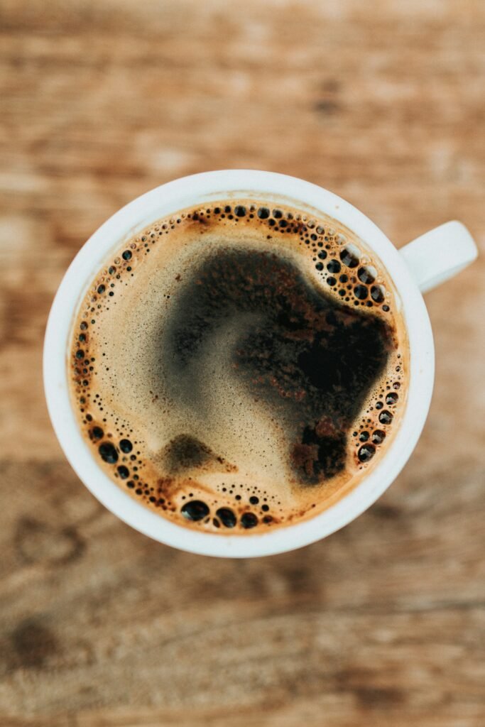 taza de café negro en taza blanca sobre mesa de madera