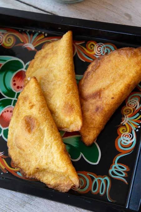 Empanadas de maíz fritas sobre bandeja decorada de madera